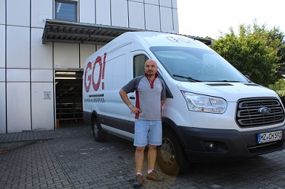 GO! Kurier mit einem Transporter vor dem offenen Lagertor geparkt